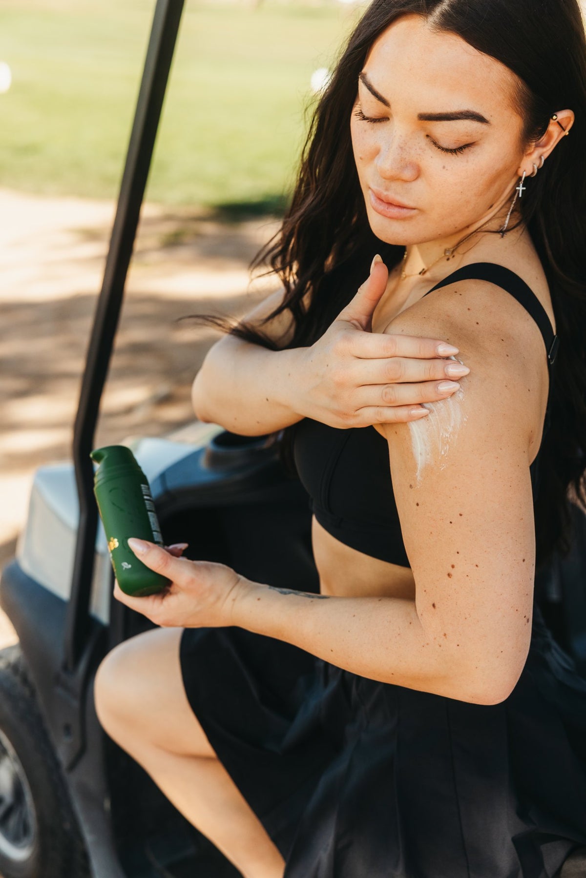Applying Arnie's Muscle Cream to the shoulder, seated in a golf cart.