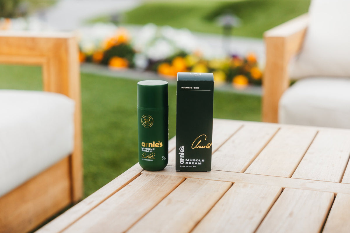 Arnie's Muscle Cream and its box on a teak patio table beside the course.